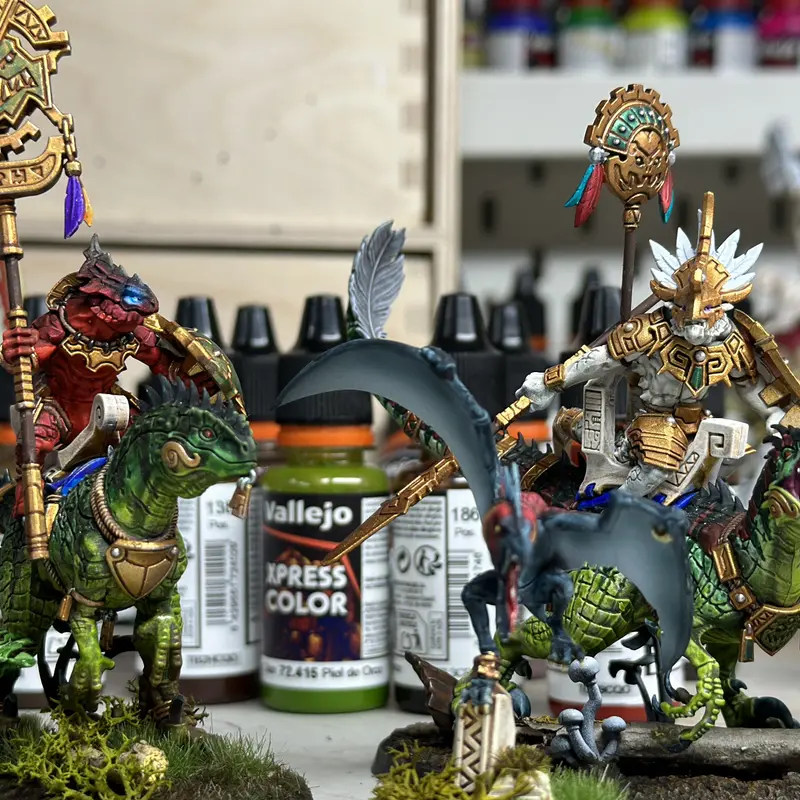 Painted mounted miniatures beside hobby paints on the bench
